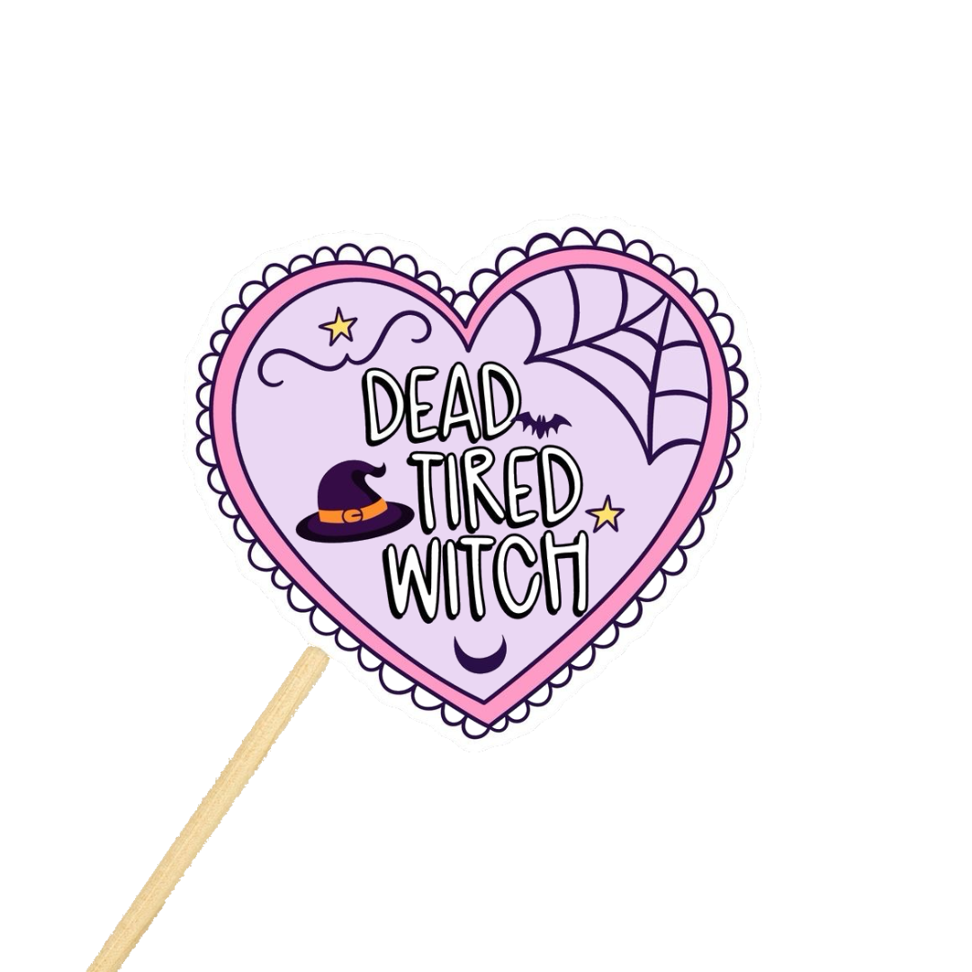 Heart-shaped sign with 'Dead Tired Witch' text and a witch hat on a stick against a white background.